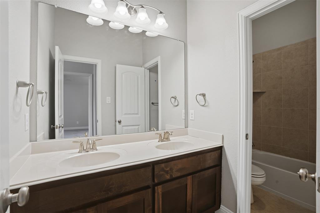2217 Riviera Drive Little Elm, TX 75068 - Photo 27 of 36 Double vanity featuring dual undermount sinks with brushed nickel fixtures, a spacious countertop, and dark wood-finish cabinetry