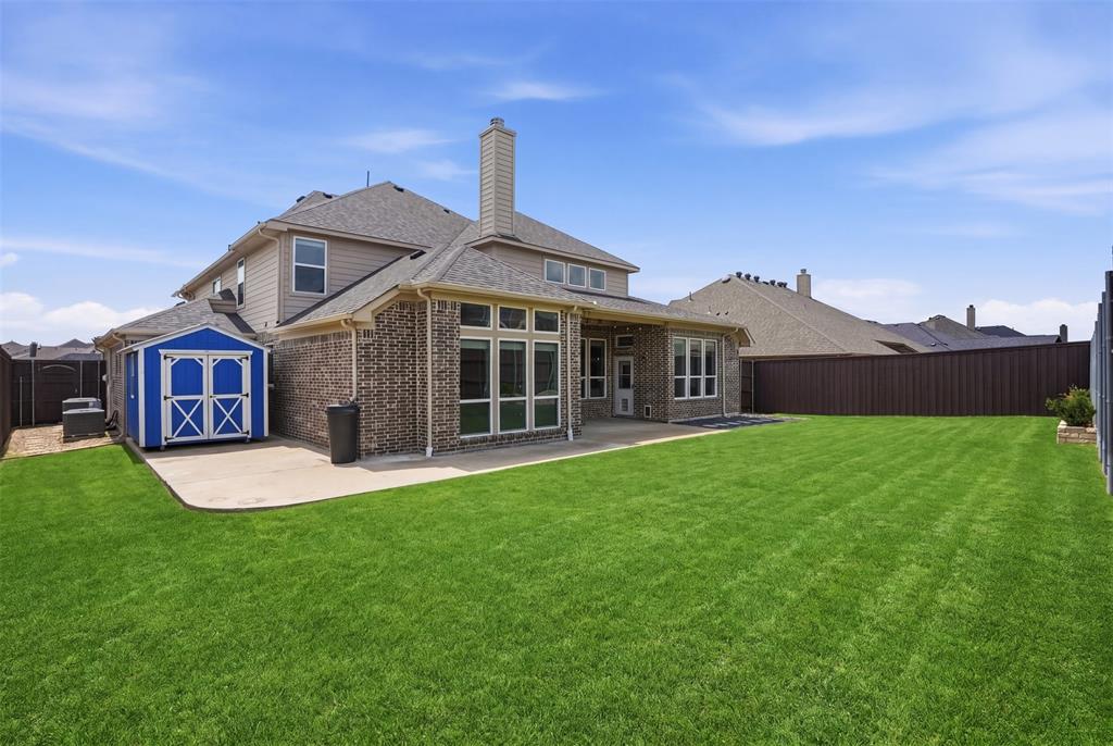 2217 Riviera Drive Little Elm, TX 75068 - Photo 31 of 36 Expansive green lawn with a concrete patio, a blue-painted storage shed, and a privacy fence