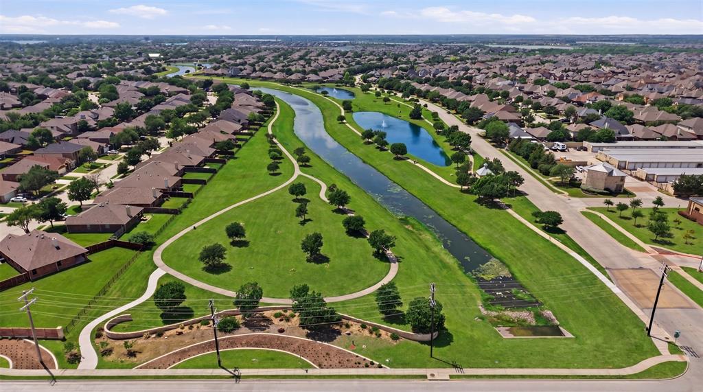 2217 Riviera Drive Little Elm, TX 75068 - Photo 35 of 36 Expansive green spaces featuring walking paths, mature trees, and a water feature with a fountain, bordered by residential properties