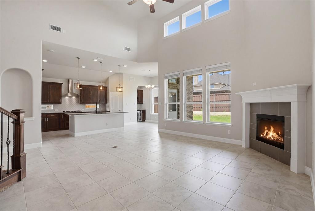 2217 Riviera Drive Little Elm, TX 75068 - Photo 5 of 36 Spacious living area featuring high ceilings, tiled flooring, a built-in fireplace with a white mantle, and large windows with transom accents