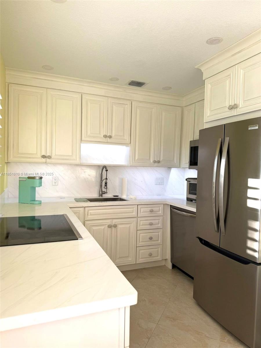 2929 Southeast Ocean Boulevard, Unit 14310 Stuart, FL 34996 - Photo 60 of 73 a kitchen with granite countertop a refrigerator sink stove and white cabinets