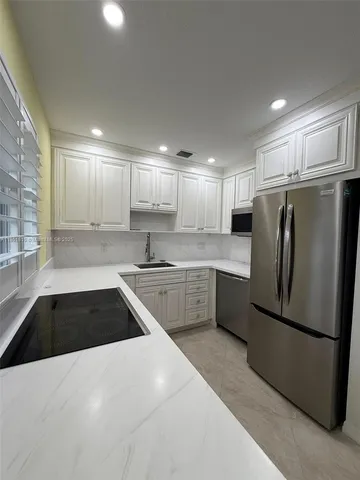 a kitchen with granite countertop a refrigerator and a sink