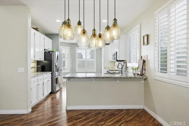 a kitchen with stainless steel appliances granite countertop a sink dishwasher a stove and a dining table with wooden floor