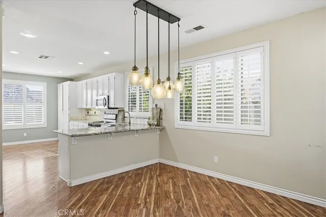 a kitchen with stainless steel appliances granite countertop a stove and a wooden floors