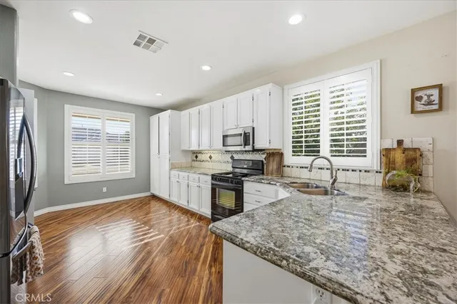 a kitchen with stainless steel appliances granite countertop sink refrigerator and window