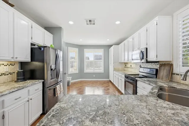 a kitchen with stainless steel appliances granite countertop a refrigerator sink and stove