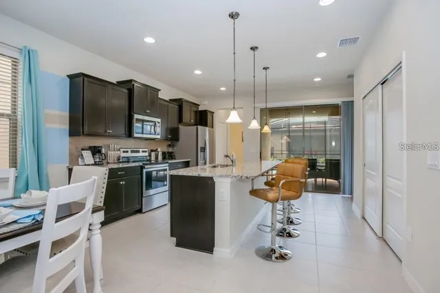 a kitchen with kitchen island stainless steel appliances a stove a sink a refrigerator cabinets a dining table and chairs