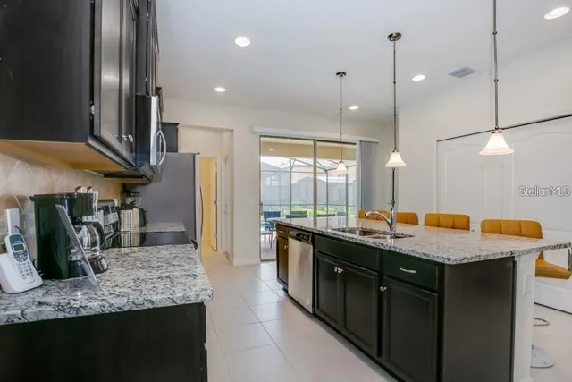 a kitchen with kitchen island granite countertop a sink a counter top space and stainless steel appliances
