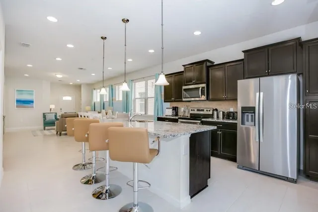 a kitchen with stainless steel appliances granite countertop a refrigerator a stove a sink a dining table and chairs