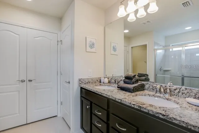 a bathroom with a granite countertop double vanity sink a mirror and shower