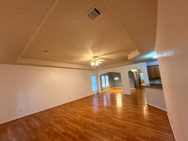 a view of an empty room with window and wooden floor