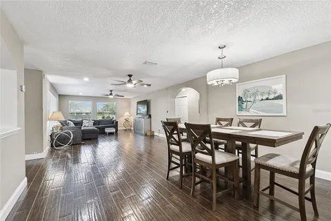 a open kitchen with stainless steel appliances granite countertop a refrigerator a sink dishwasher a stove and a dining table with wooden floor