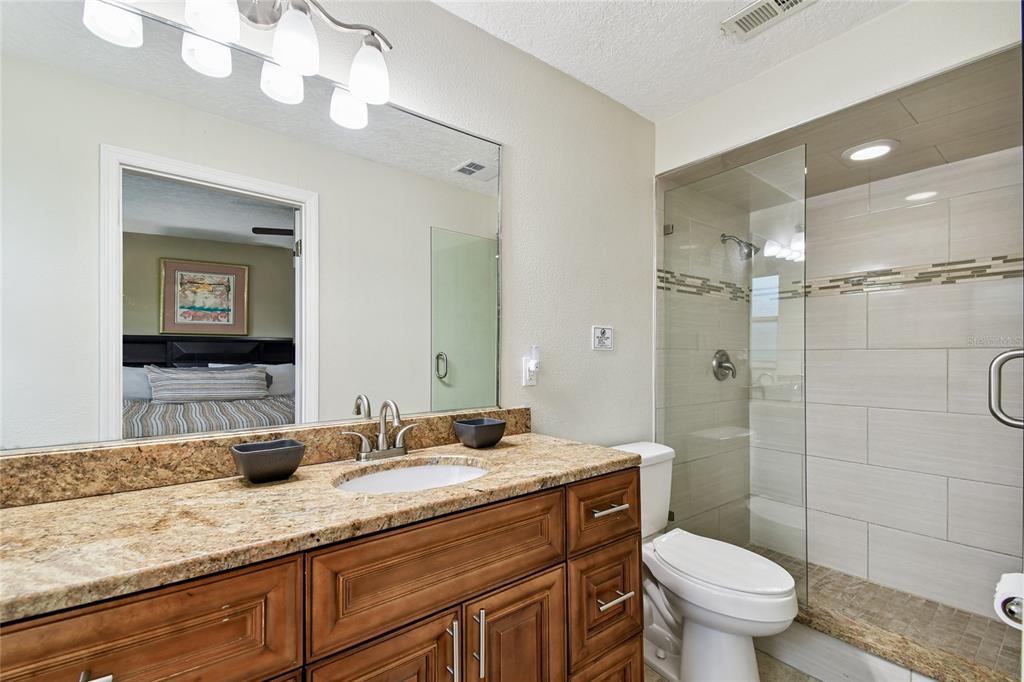 1948 Belleair Road Clearwater, FL 33764 - Photo 26 of 84 a bathroom with a granite countertop sink a toilet and a mirror