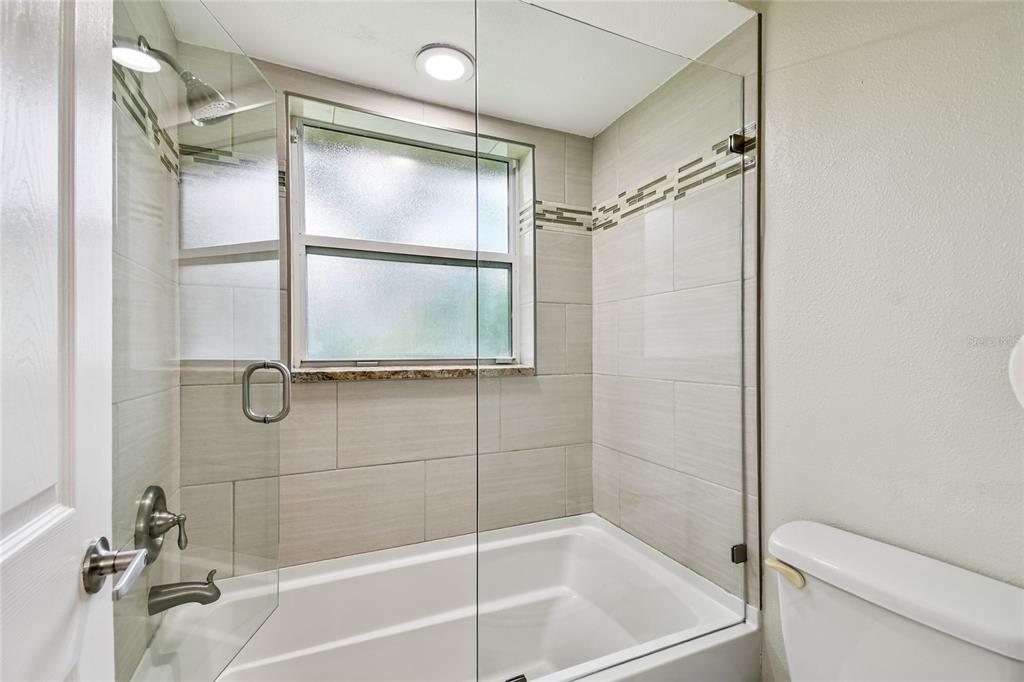 1948 Belleair Road Clearwater, FL 33764 - Photo 32 of 84 a bathroom with a glass shower door