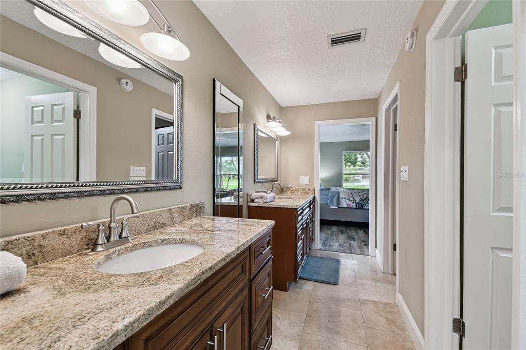 1948 Belleair Road Clearwater, FL 33764 - Photo 41 of 84 a en suite bathroom with a granite countertop sink and a mirror