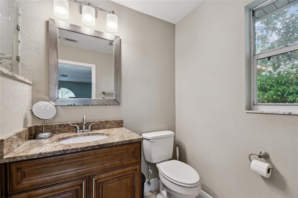 1948 Belleair Road Clearwater, FL 33764 - Photo 65 of 84 a bathroom with a granite countertop toilet sink and mirror