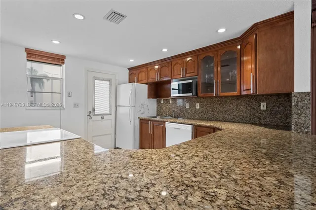 a large kitchen with stainless steel appliances granite countertop a granite counter tops and a stove top oven