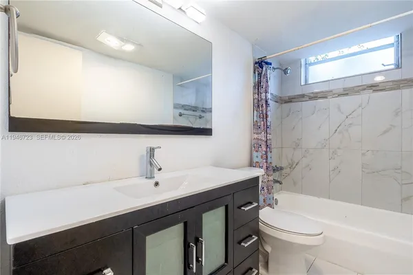 a bathroom with a sink a toilet a mirror and shower