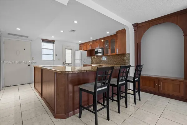 a kitchen with stainless steel appliances granite countertop a chairs and a refrigerator