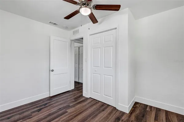 a view of empty room with wooden floor and ceiling fan