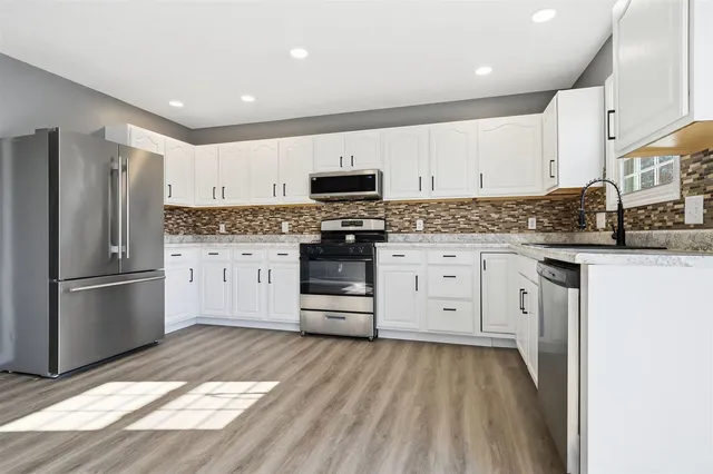 a kitchen with granite countertop a refrigerator stove top oven and sink