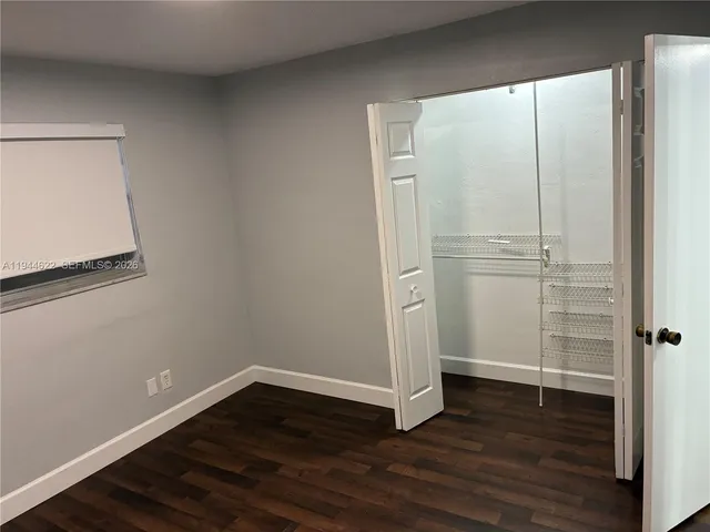 a view of an empty room with wooden floor and closet
