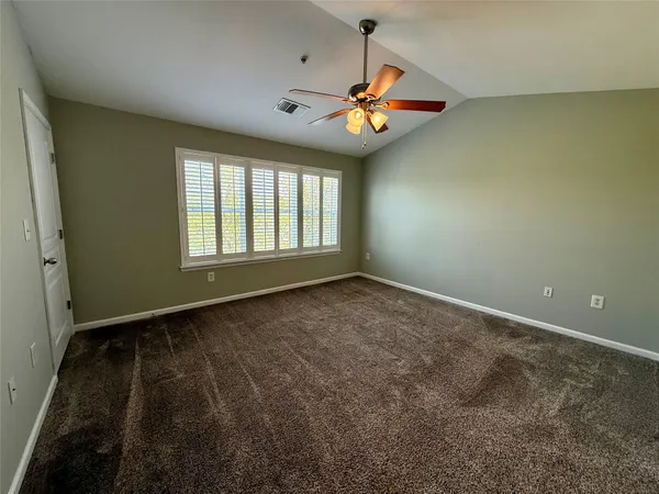 en empty room with windows and ceiling fan