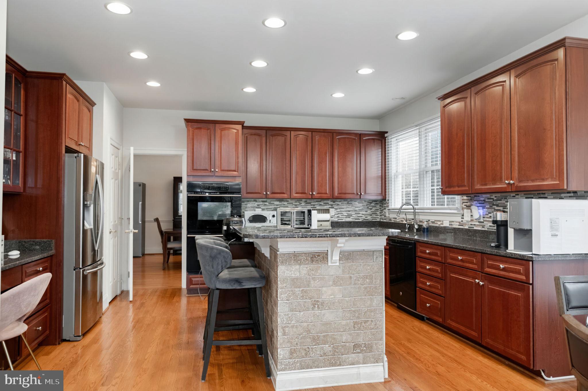 11375 Harding Road Laurel, MD 20723 - Photo 11 of 40 a kitchen with kitchen island granite countertop wooden cabinets stainless steel appliances a sink and a center island