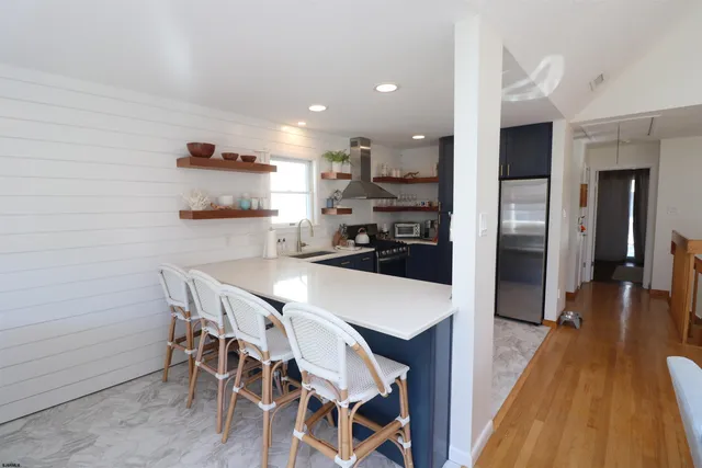 a kitchen with stainless steel appliances a dining table chairs and wooden floor