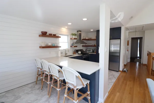 a kitchen with stainless steel appliances a dining table chairs and wooden floor