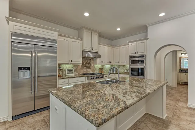 a kitchen with stainless steel appliances granite countertop a sink and a refrigerator