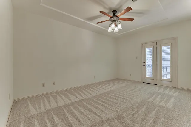 a view of an empty room with chandelier fan