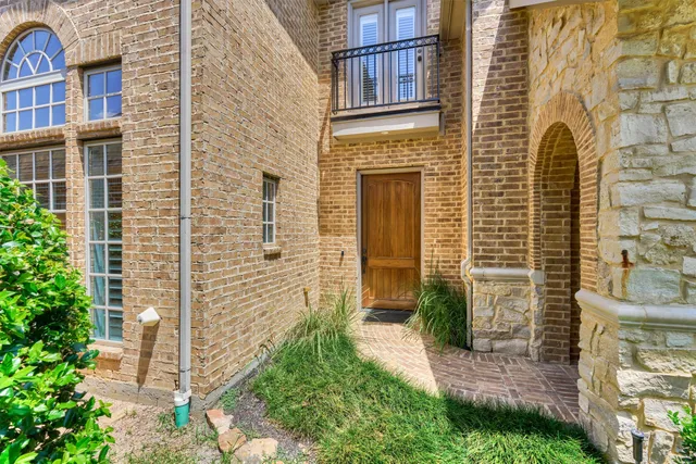 a view of a brick house with a yard and plants