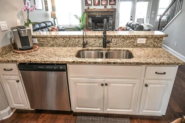 a close view of a sink and dishwasher with wooden floor