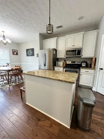 a kitchen with stainless steel appliances granite countertop a sink a stove a refrigerator cabinets and chairs