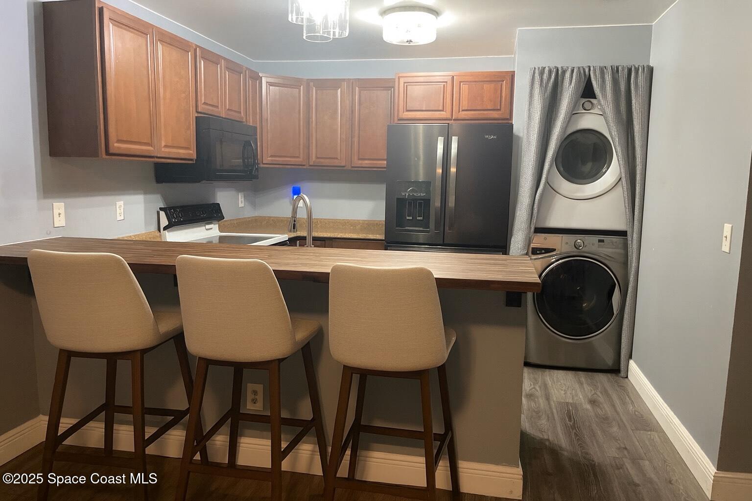 1040 Abada Court Northeast, Unit 109 Palm Bay, FL 32905 - Photo 9 of 25 a kitchen with stainless steel appliances granite countertop a table chairs and a refrigerator