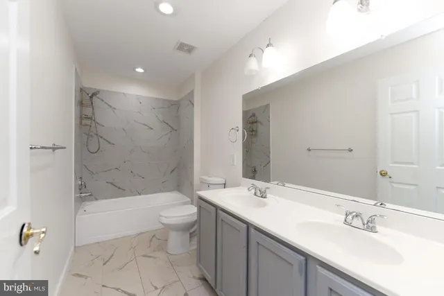 a bathroom with a bathtub shower sink mirror and toilet