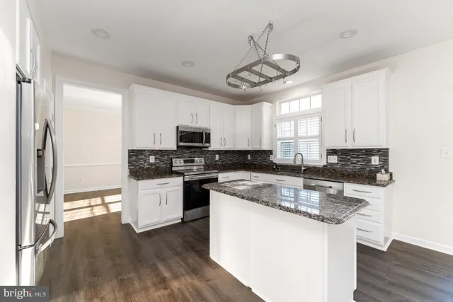 a kitchen with stainless steel appliances granite countertop a sink a stove and refrigerator