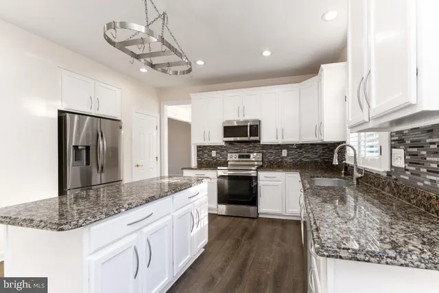 a kitchen with stainless steel appliances granite countertop a sink a stove top oven a counter space and cabinets