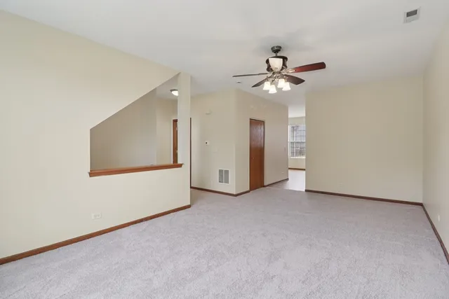 an empty room with chandelier fan and windows