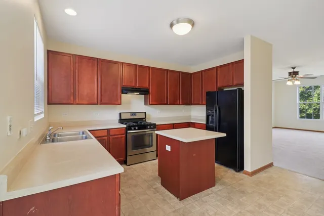 a kitchen with stainless steel appliances granite countertop a refrigerator stove a sink and dishwasher with wooden cabinets