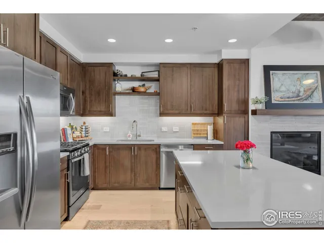 a kitchen with stainless steel appliances kitchen island granite countertop a refrigerator a sink dishwasher a stove with wooden cabinets