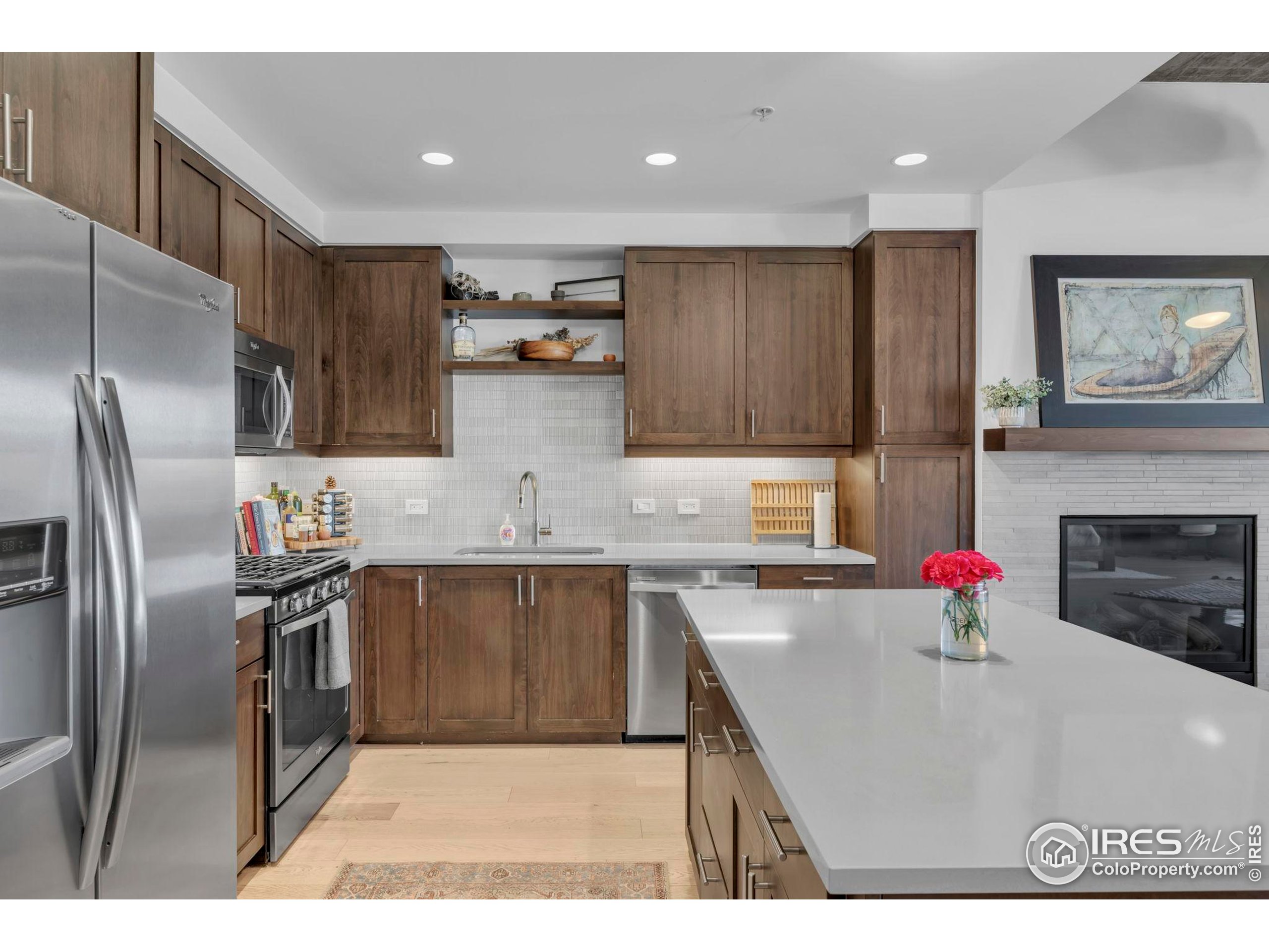 3301 Arapahoe Avenue, Unit 405 Boulder, CO 80303 - Photo 5 of 36 a kitchen with stainless steel appliances kitchen island granite countertop a refrigerator a sink dishwasher a stove with wooden cabinets