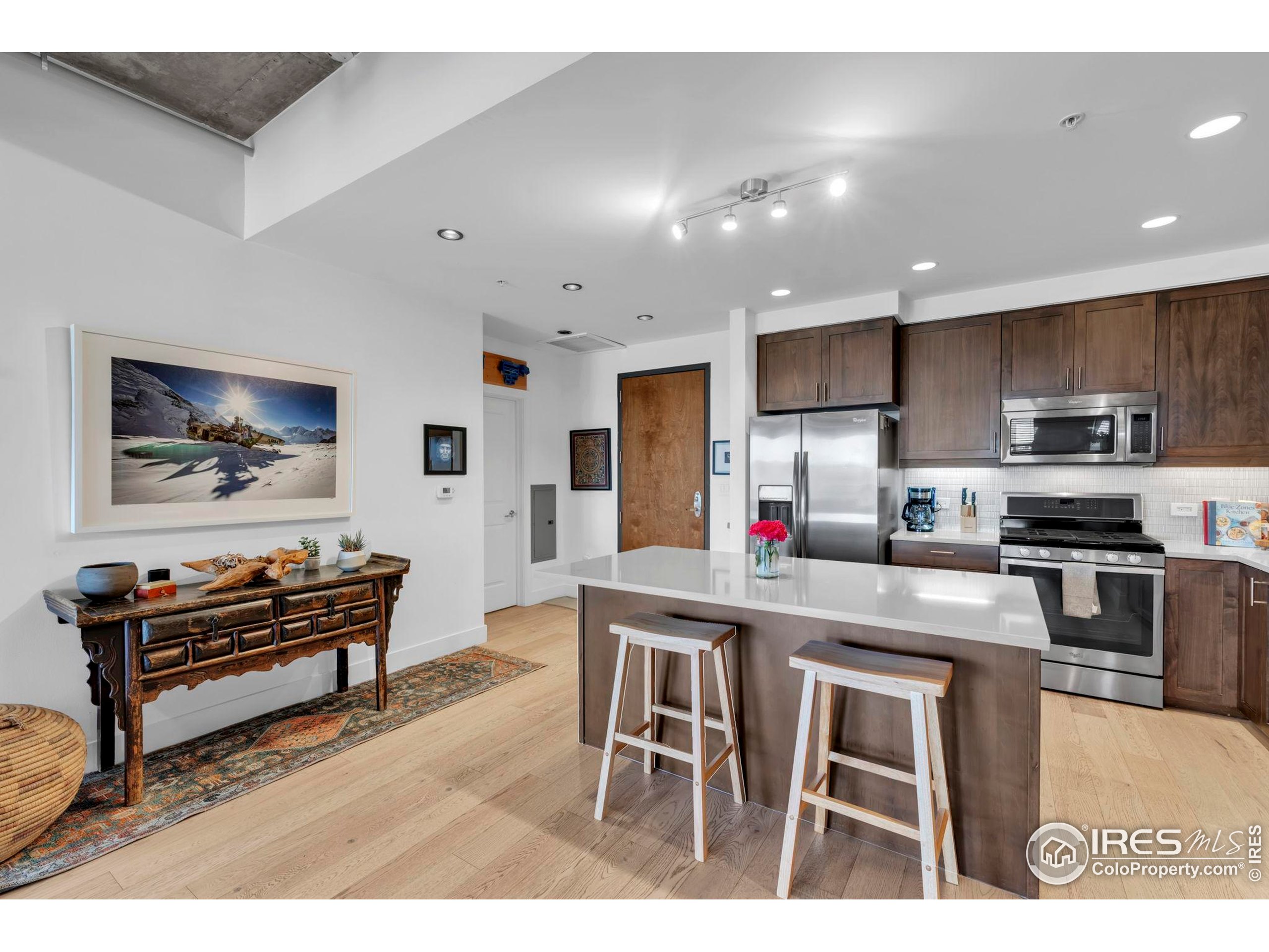 3301 Arapahoe Avenue, Unit 405 Boulder, CO 80303 - Photo 9 of 36 a kitchen with stainless steel appliances granite countertop a stove top oven a sink a dining table and chairs with wooden floor