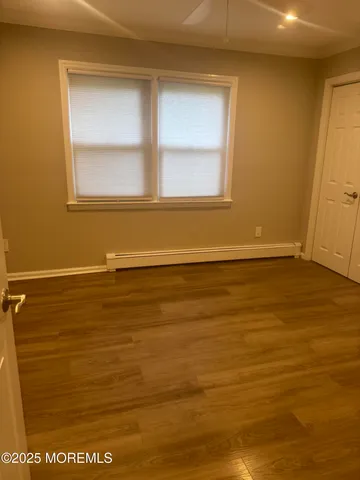 a view of a room with wooden floor and small window