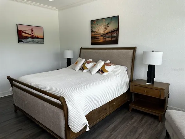a bedroom with bed lamp and wall painting on the wall