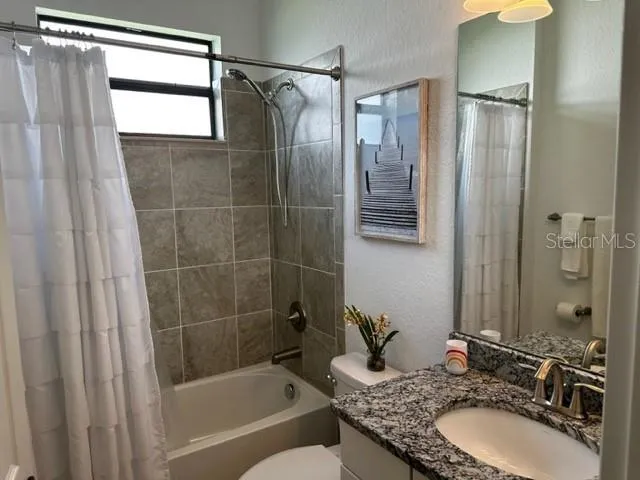 a bathroom with a granite countertop shower sink and mirror