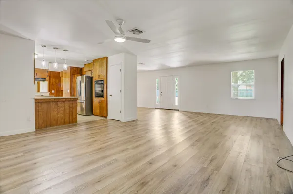 a view of a kitchen with wooden floor a ceiling fan and windows