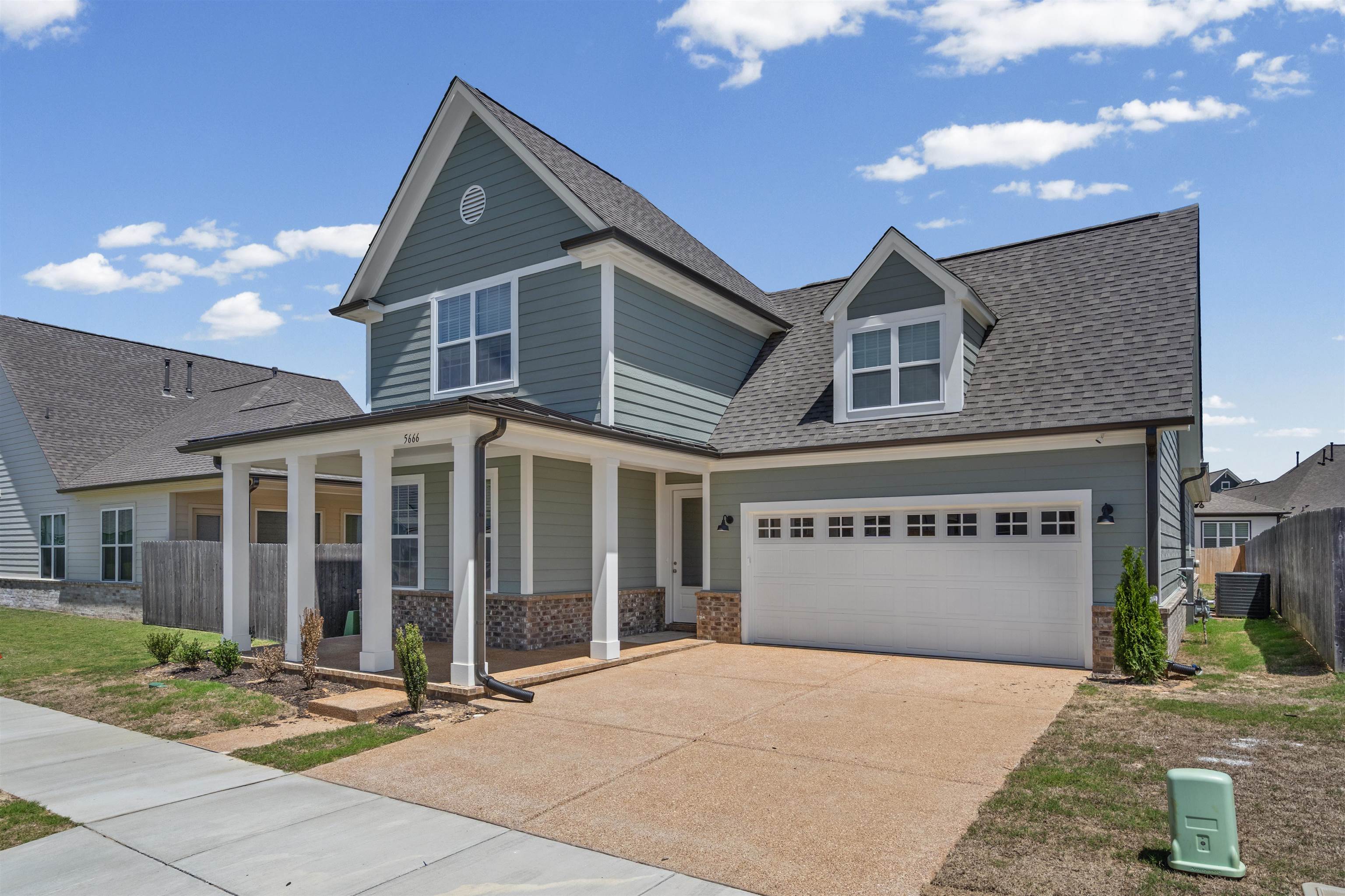5666 Pleasant Pk Place Arlington, TN 38002 - Photo 2 of 27 Contemporary residence featuring light blue siding with white trim, a covered porch with pillars, an attached garage with decorative windows, and a dormer window
