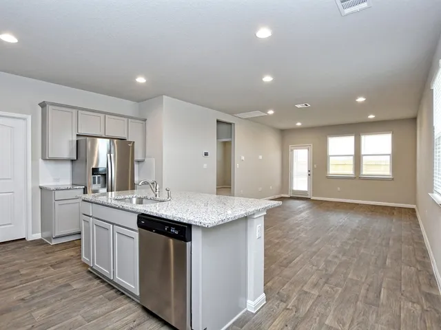 a large kitchen with stainless steel appliances kitchen island a large counter top a sink a refrigerator and a stove